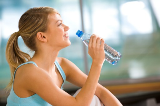 woman drinking from disposable plastic water bottle
