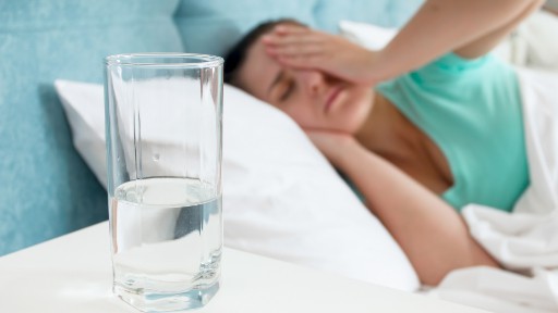 woman in bed sick with glass of water